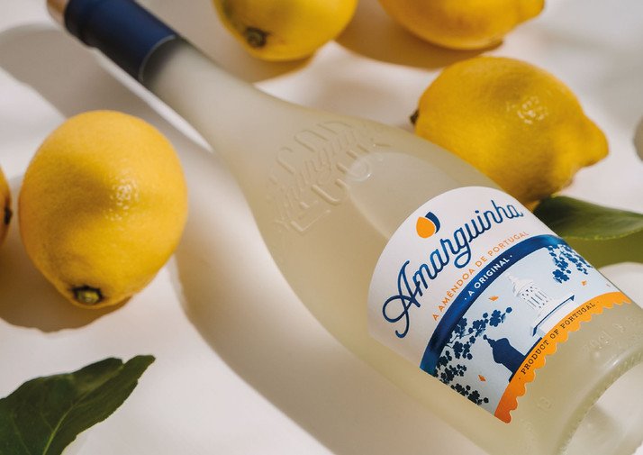Amendoa Amarguinha bottle laying down close up with lemons Almond liqueur
